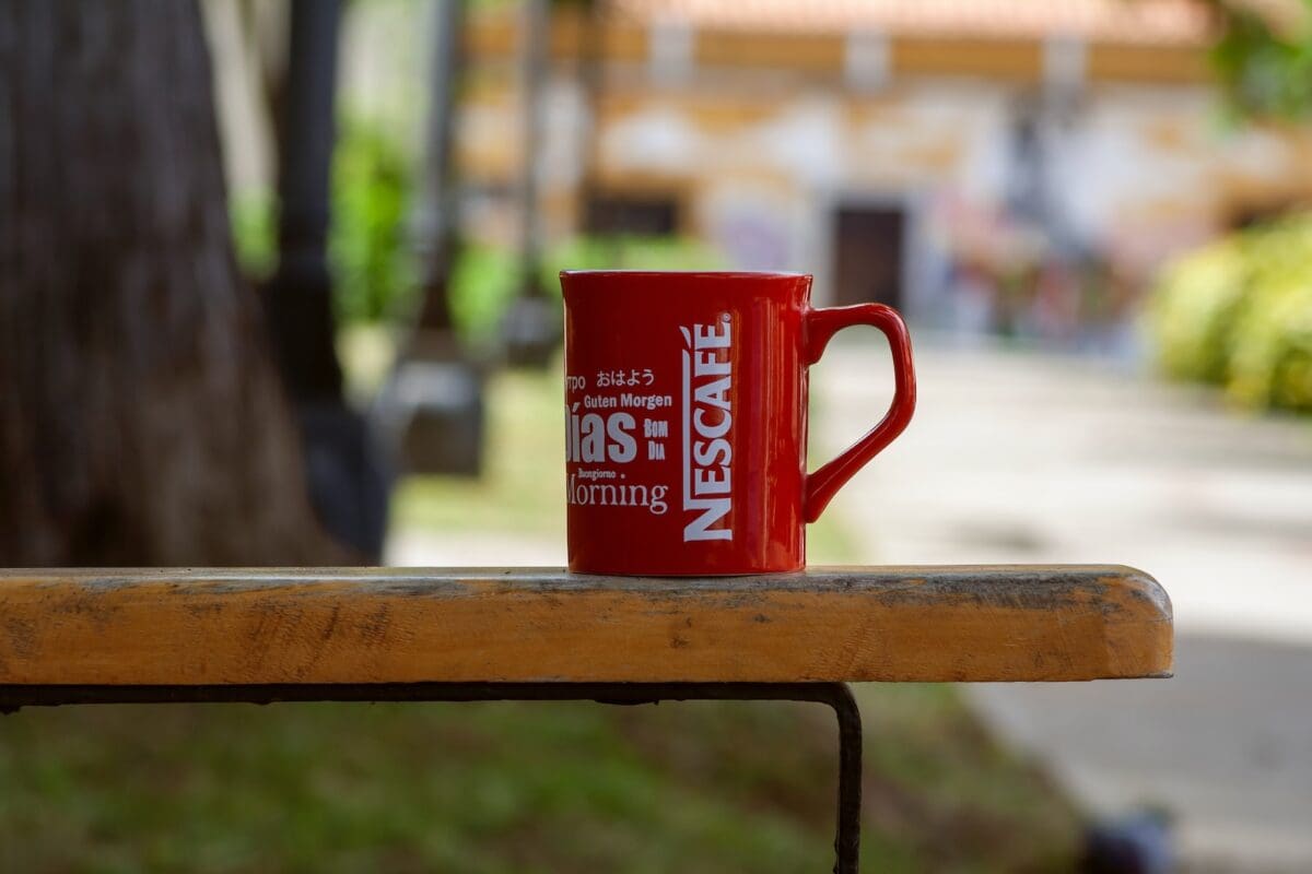 a red cup with the words nescafe, placed on a wooden table