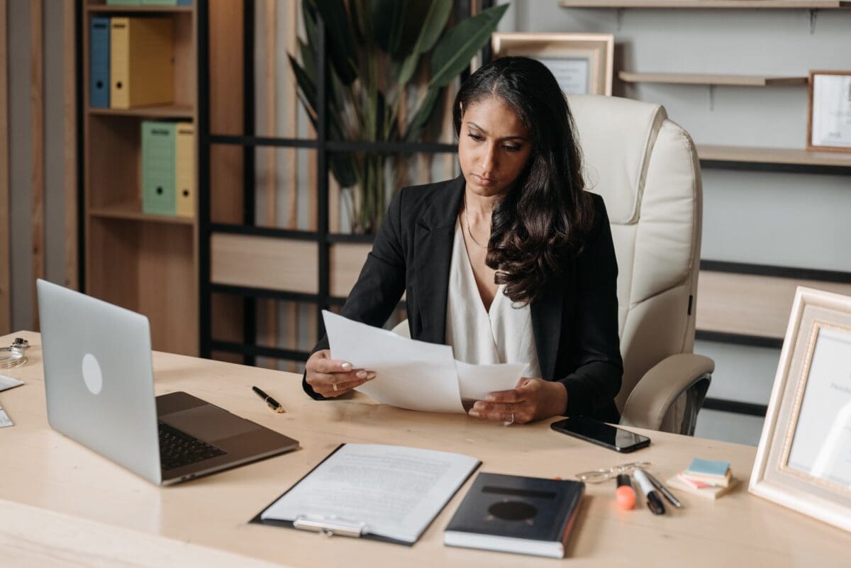 a businesswoman at her desk with a laptop and reading papers