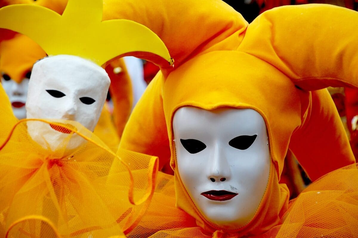 parade of clowns and jester with yellow costumes and white face mask