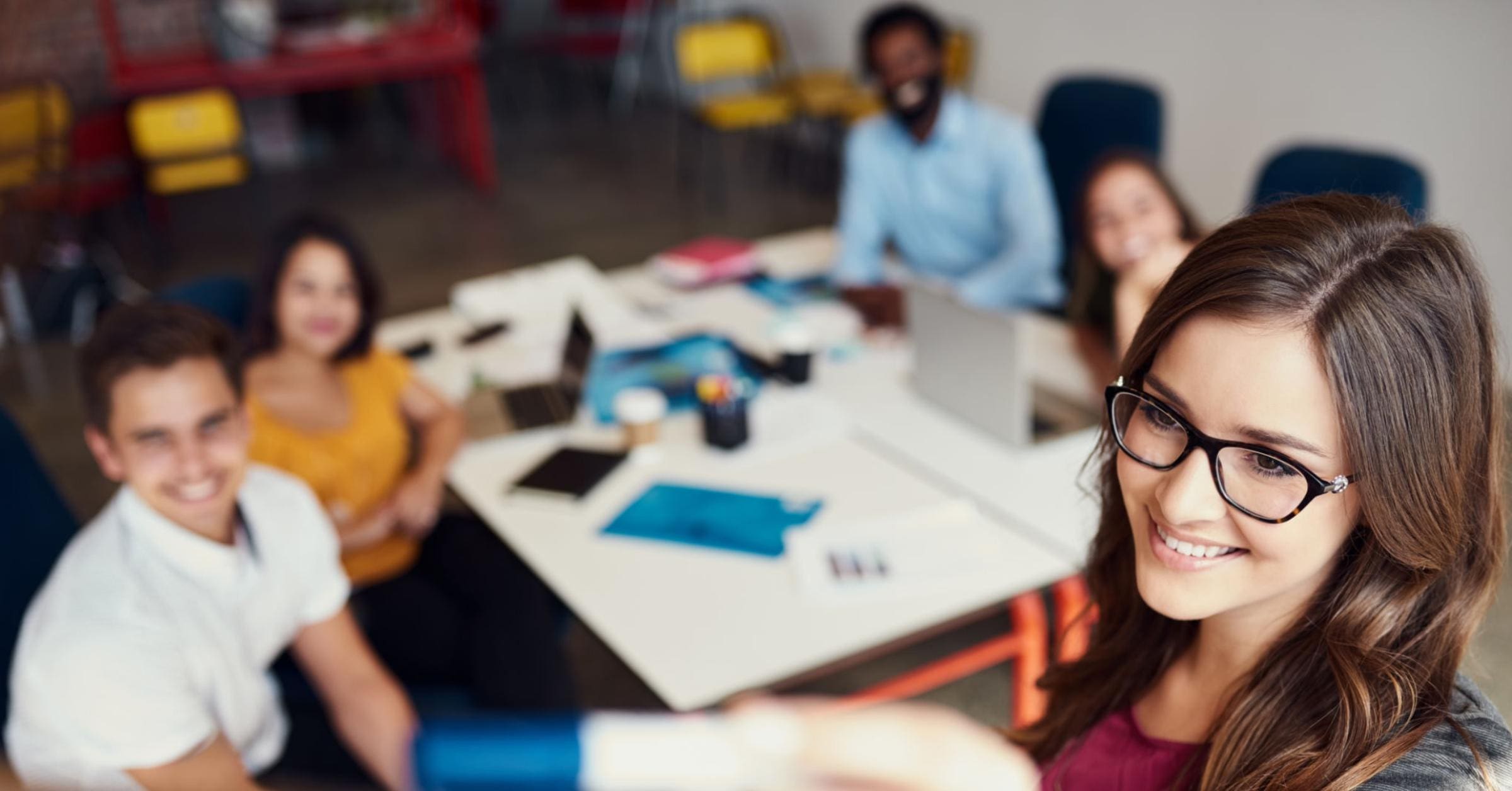A group of diverse business professionals discussing and collaborating in a modern office setting, with a focus on their engaged expressions and body language.